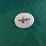 Scrimshaw pin featuring a small sail boat. Signed "Nunuk" on the front.